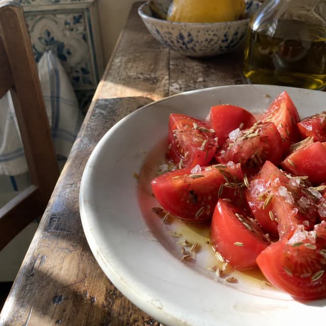 Pomodori con olio, sale al cedro e semi di finocchietto su un piatto in cucina.
